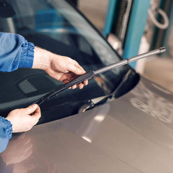 technician replacing windshield wipers on car